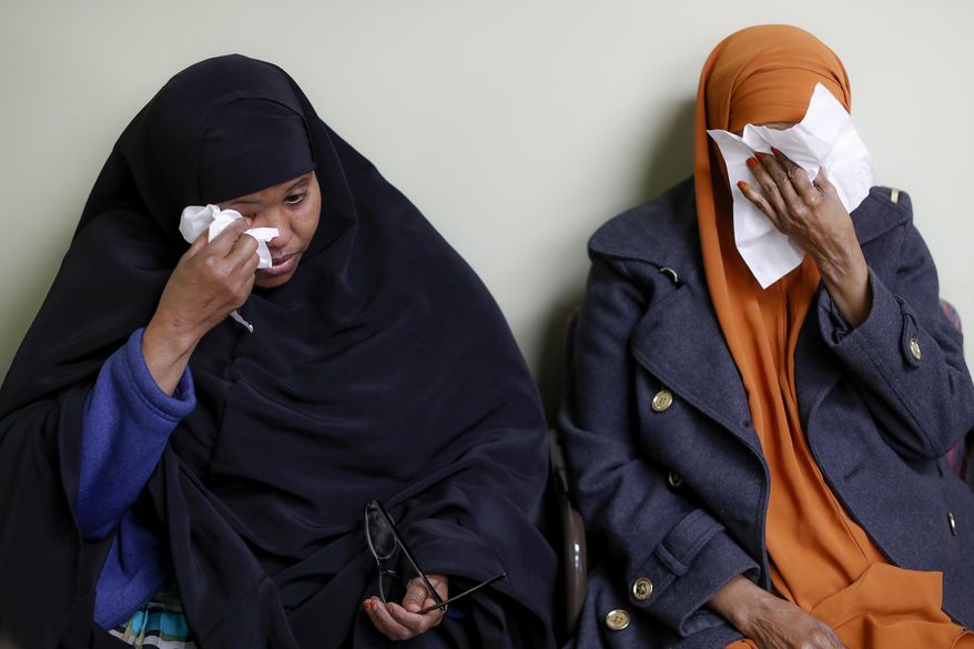 FILE - In this March 16, 2017, file photo, Somali refugees Layla Muali, left, and Hawo Jamile, right, wipe away tears during an interview at the Community Refugee & Immigration Services offices in Columbus, Ohio. Columbus has the country's largest percentage of Somali refugees. A federal judge in Hawaii further weakened the already-diluted travel ban in a ruling Thursday, July 13, 2017, by vastly expanding the list of U.S. family relationships that visitors from six Muslim-majority countries can use to get into the country. (AP Photo/John Minchillo, File)