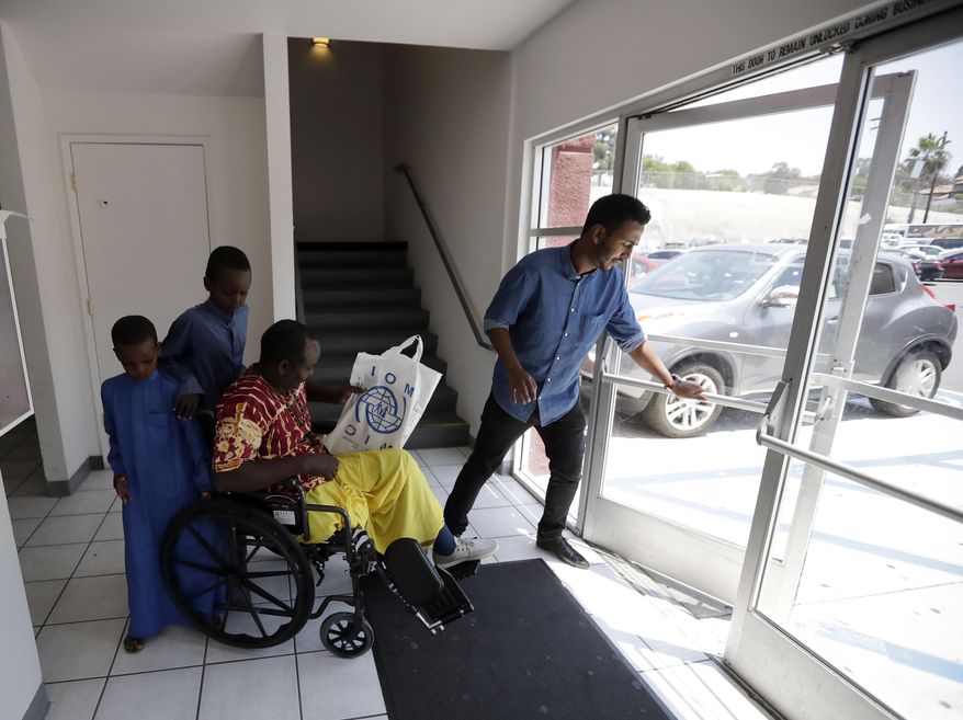 FILE - In this July 6, 2017, file photo, Ali Said, of Somalia, center, leaves a center for refugees with his two sons, as refugee caseworker Mohamed Yassin, right, holds open the door in San Diego. A federal judge in Hawaii further weakened the already-diluted travel ban Thursday, July 13, 2017, by vastly expanding the list of U.S. family relationships that visitors from six Muslim-majority countries can use to get into the country. (AP Photo/Gregory Bull, File)
