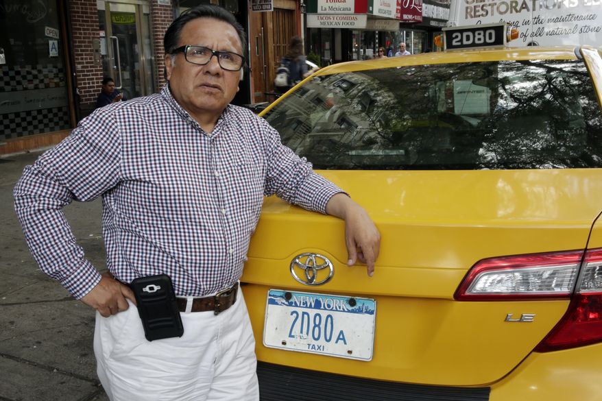 In this June 26, 2017 photo, taxi driver and taxi medallion owner Marcelino Hervias poses for photos with his taxicab on New York's Upper West Side. Just three years ago, cab owners and investors were paying as much as $1.3 million for a medallion. Now they are worth less than half that amount. (AP Photo/Richard Drew)
