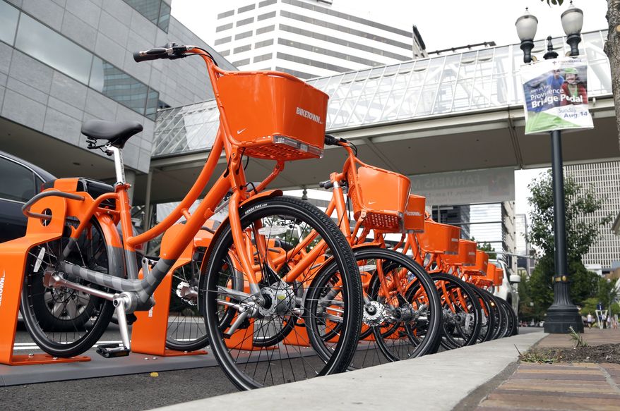 Bicycles stand at the ready for use in a bike-sharing program in Portland, Ore., Tuesday, July 19, 2016. One-thousand bikes will be available for a fee after the system goes online Tuesday with bikes located at orange-colored racks throughout much of the city. The Nike-sponsored program, called Biketown, is taking off three years later than what city leaders originally envisioned. (AP Photo/Don Ryan)