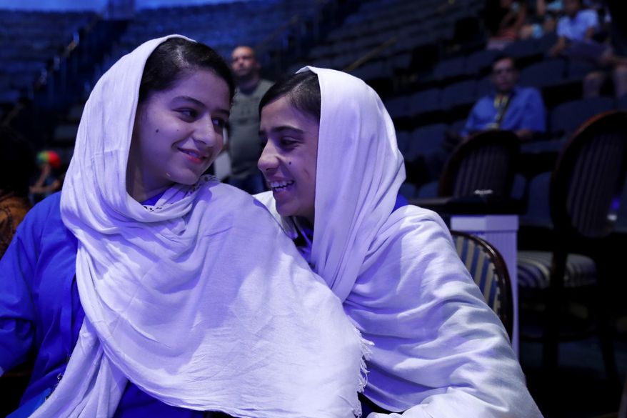 Kawsar Roshan, and Somayeh Faruqi, smile as their team takes to the floor as the watch members of their Afghanistan team prepare to compete in the FIRST Global Robotics Challenge, Monday, July 17, 2017, in Washington. The challenge is an international robotics event with teams from over 100 countries. (AP Photo/Jacquelyn Martin)