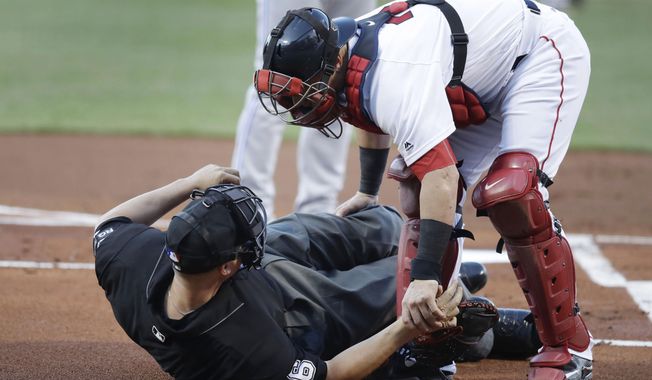 Boston Red Sox catcher Christian Vazquez aids home plate umpire Chris Segal after he was accidentally hit on the head by Toronto Blue Jays' Josh Donaldson's bat during the first inning of a baseball game at Fenway Park in Boston, Monday, July 17, 2017.( AP Photo/Charles Krupa)