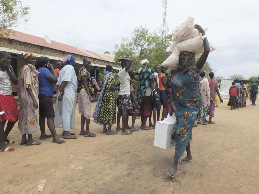 FILE - In this April 19, 2017, file photo, a South Sudanese woman carries food donated by Saudi Arabia Government through the Islamic Council of South Sudan, in Juba, South Sudan. Eight of the largest U.S.-based aid groups are joining together in a new campaign to address what the United Nations calls the world's largest humanitarian crisis in more than 70 years. More than 20 million people are at risk of famine in nine African nations and Yemen, but Richard Stearns, president of Federal Way, Washington-based World Vision, says it has been overshadowed amid the controversies surrounding President Donald Trump's administration. (AP Photo/Samir Bol, File)
