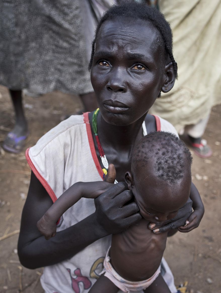 FILE - In this file photo taken April 5, 2017, Abuk Garang holds her 7-month-old son William Deng as she and others walk to a food distribution site in Malualkuel in the Northern Bahr el Ghazal region of South Sudan. Eight of the largest U.S.-based aid groups are joining together in a new campaign to address what the United Nations calls the world's largest humanitarian crisis in more than 70 years. More than 20 million people are at risk of famine in nine African nations and Yemen, but Richard Stearns, president of Federal Way, Washington-based World Vision, says it has been overshadowed amid the controversies surrounding President Donald Trump's administration. (AP Photo, File)