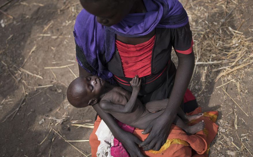 FILE - In this April 5, 2017 file photo, Adel Bol, 20, cradles her 10-month-old daughter Akir Mayen at a food distribution site in Malualkuel, in the Northern Bahr el Ghazal region of South Sudan. Eight of the largest U.S.-based aid groups are joining together in a new campaign to address what the United Nations calls the world's largest humanitarian crisis in more than 70 years. More than 20 million people are at risk of famine in nine African nations and Yemen, but Richard Stearns, president of Federal Way, Washington-based World Vision, says it has been overshadowed amid the controversies surrounding President Donald Trump's administration. (AP Photo, File)