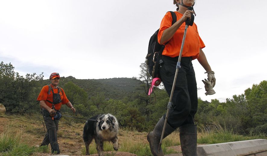 Members of the Tonto Rim Search and Rescue team exit a section of forest after searching along the banks of the East Verde River for victims of a flash flood, Sunday, July 16, 2017, in Payson, Ariz. Search and rescue crews, including 40 people on foot and others in a helicopter, have recovered bodies of children and adults, some as far as two miles down the river after Saturday&#x27;s flash flooding poured over a popular swimming area inside the Tonto National Forest in central Arizona. (AP Photo/Ralph Freso)