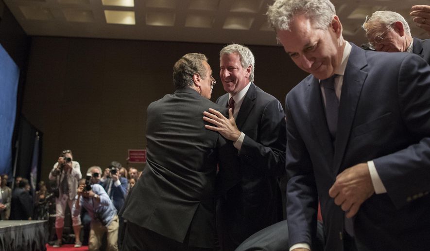New York Governor Andrew Cuomo, left, and New York City Mayor Bill de Blasio, center, hug after Cuomo spoke during a rally in support of the Affordable Care Act and against the Senate replacement bill, Monday, July 17, 2017, in New York. (AP Photo/Mary Altaffer)