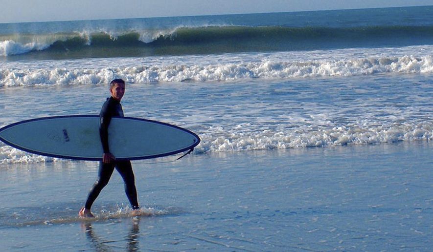 In this August 2010 photo provided by Harry Martin, then-U.S. Army Gen. Michael Flynn carries his surfboard on Sachuest Beach, in Middletown, R.I. The former National Security Adviser, at the center of multiple probes into Russia&#x27;s interference in the 2016 presidential election, is seeking sanctuary from the swirling eddy of news coverage in the beach town where he grew up. (Harry Martin via AP)