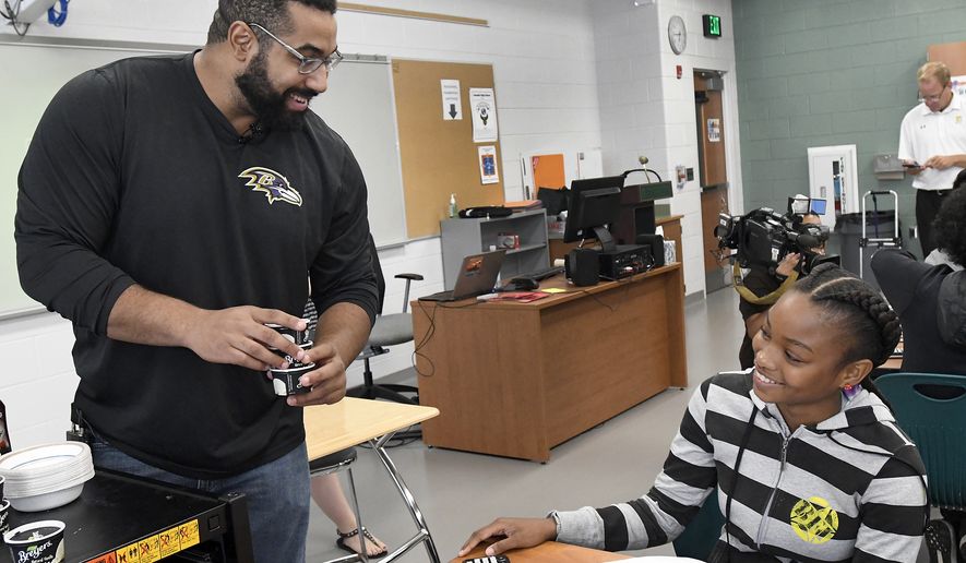 IMAGE DISTRIBUTED FOR TEXAS INSTRUMENTS - Baltimore Ravens lineman and math scholar John Urschel, left, hands out ice cream to Chelsy Valerio, 14, of Baltimore, during a STEM lesson at Dundalk High School during the launch of Texas Instruments&#39; STEM Behind Cool Careers series on Tuesday, July 18, 2017 in Baltimore. The fun, free activities show students how a solid understanding of STEM subjects is vital for any career, even careers students least expect. (Steve Ruark/AP Images for Texas Instruments)