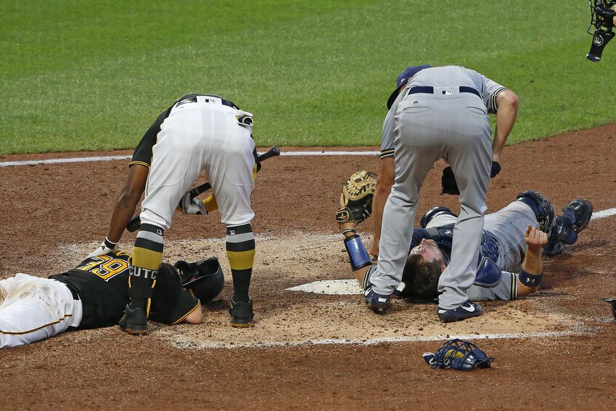 Pittsburgh Pirates&#39; Chad Kuhl, left, and Milwaukee Brewers catcher Stephen Vogt, right, lie on the ground after a collision at home plate during the fifth inning of a baseball game in Pittsburgh, Monday, July 17, 2017. Both players were shaken up on the play and Vogt left the game. Checking on their teammates are Pirates&#39; Andrew McCutchen, top left, and Brewers starting pitcher Brent Suter. (AP Photo/Gene J. Puskar)