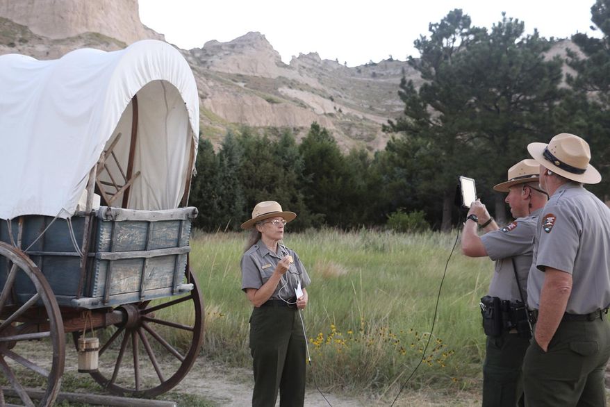 In a Sunday, July 16, 2017 photo, Park Ranger Lesley Gaunt, lead interpreter, discusses how emigrants traveled west to students from Afghanistan via the internet. Park Superintendent Dan Morford, lead interpreter Lesley Gaunt and Chief Ranger Justin Cawiezel were at the Scotts Bluff National Monument on Sunday to give more than 60 Afghan students a virtual tour through an iPad. (Irene North/The Star-Herald via AP)