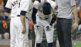 Houston Astros&#39; Yuli Gurriel, left, watches as Carlos Correa has his left hand looked at by manager A.J. Hinch and trainer Jeremiah Randall, right, during the fourth inning of the team&#39;s baseball game against the Seattle Mariners on Monday, July 17, 2017, in Houston. Correa left the game. (Melissa Phillip/Houston Chronicle via AP)
