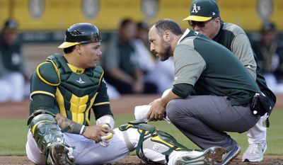 Oakland Athletics catcher Bruce Maxwell, left, is examined by trainer Nick Paparesta and manager Bob Melvin, right, after being hit on the head by a ball fouled by Tampa Bay Rays&#x27; Brad Miller during the second inning of a baseball game Monday, July 17, 2017, in Oakland, Calif. (AP Photo/Ben Margot)