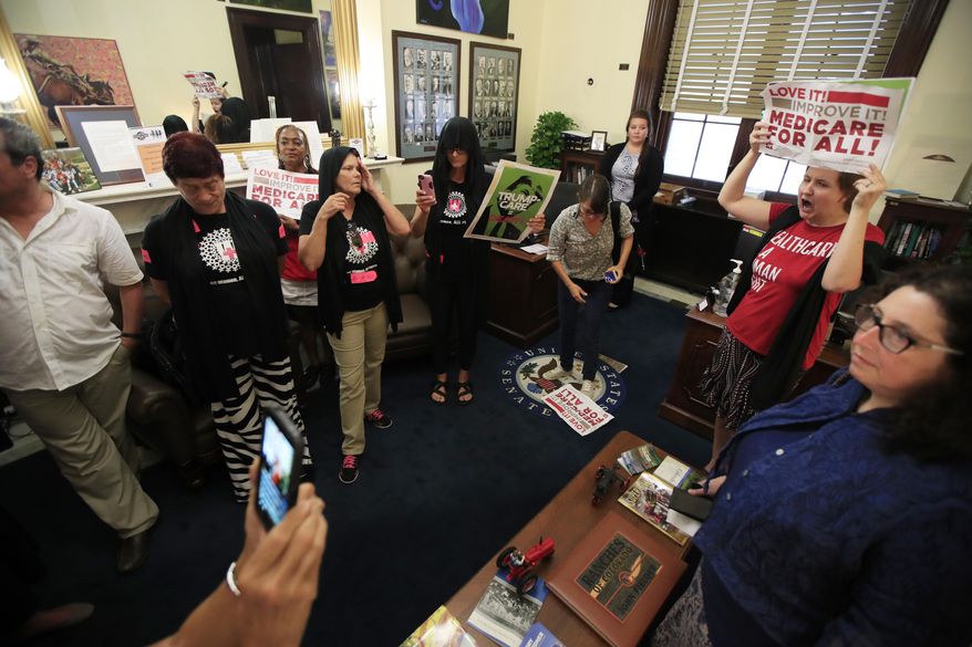 Protesters against the Republic health care proposals chant slogans and wave protest banners inside the office of Sen. Cory Gardner, R-Colo., at the Russell Senate Office building on Capitol Hill in Washington, Wednesday, July 19, 2017. (AP Photo/Manuel Balce Ceneta)
