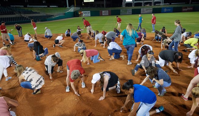 Arkansas Travelers female fans search the infield for a buried diamond ring during the teams annual &quot;Diamond Dig&quot;, presented by Lee Ann&#x27;s Fine Jewelry, after a game against the Midland RockHounds on May 25, 2017 at Dickey-Stephens Park in Little Rock, Arkansas.  Midland defeated Arkansas 8-1.  (Mike Janes/Four Seam Images via AP)