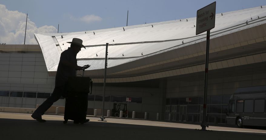 In this Tuesday, June 27, 2017. photo, a traveler walks towards terminal D at Dallas/Fort Worth International Airport in Grapevine, Texas. The steel style roof of the terminal was built using a cladding product that is believed to have been a major contributor to the London apartment tower fire. In sales brochures, a U.S. company boasted of the “stunning visual effect” its shimmering aluminum panels created in an NFL stadium, an Alaskan school and a 33-story hotel on Baltimore’s waterfront. Those same panels also were used in London’s Grenfell Tower. (AP Photo/LM Otero)