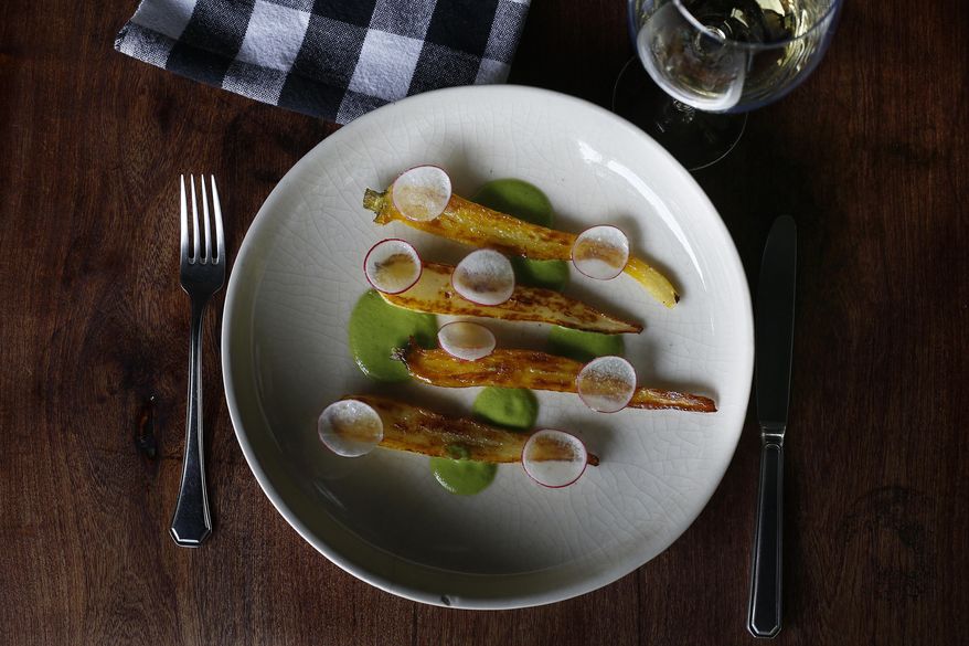 This July 14, 2017 photo shows a plate garnished with chinampa-grown roasted yellow carrots with asparagus puree, prepared by chef Eduardo Garcia, founder of Maximo Bistrot and a former U.S. migrant worker, at his restaurant in Mexico City. Diners reserve weeks in advance for a coveted table at Maximo Bistrot, one of three restaurants Garcia runs. (AP Photo/Marco Ugarte)