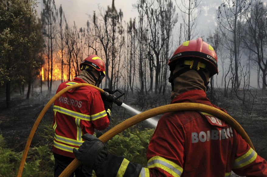 FILE- In this Sunday, June 18, 2017, file photo, Portuguese firefighters work to stop a forest fire from reaching the village of Figueiro dos Vinhos in central Portugal. Portuguese lawmakers agreed Wednesday, July 19, 2017, on new measures to help contain the fires that race through the country&#39;s forests each summer, after one wildfire last month that killed 64 people. (AP Photo/Paulo Duarte, file)