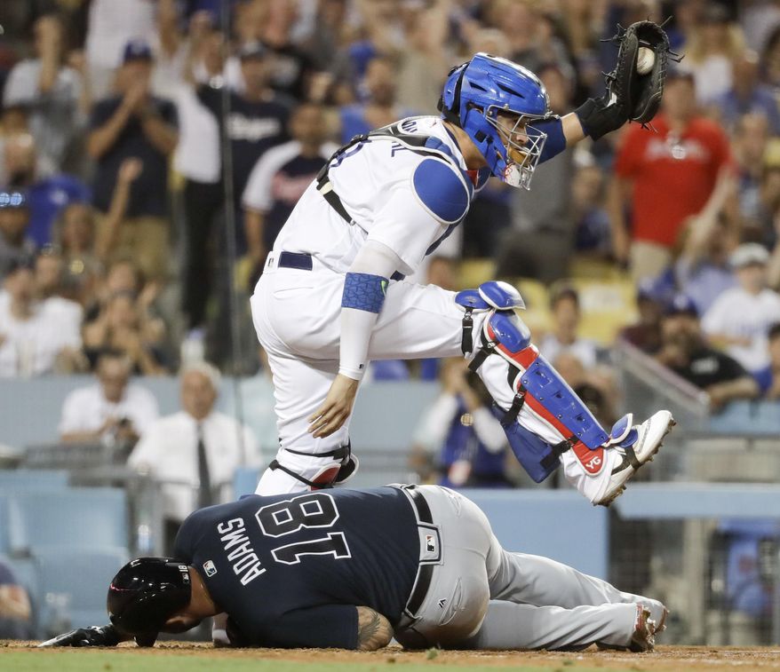 Atlanta Braves' Matt Adams lies on the ground after a collision with Los Angeles Dodgers catcher Yasmani Grandal during the eighth inning of a baseball game in Los Angeles, Thursday, July 20, 2017. Adams was called out at home. (AP Photo/Chris Carlson)