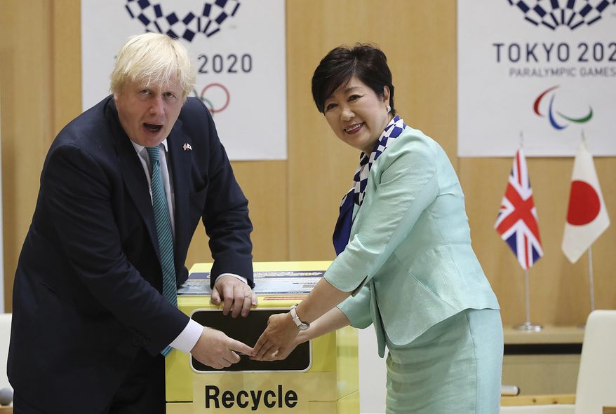 Britain's Foreign Secretary Boris Johnson, left, and Tokyo Gov. Yuriko Koike, right, tosses an unused mobile phone in to a recycle bin prior to their meeting at the Tokyo Metropolitan government office in Tokyo Friday, July 21, 2017. Organizers of the 2020 Tokyo Olympics collect discarded electronic devices that will be used in the production of the medals to be awarded to athletes. (AP Photo/Eugene Hoshiko)