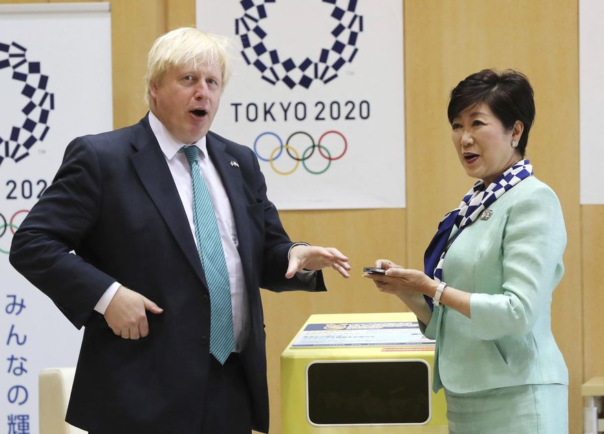 Britain's Foreign Secretary Boris Johnson, left, and Tokyo Gov. Yuriko Koike, right, chat before tossing an unused mobile phone to a recycle bin prior to their meeting at the Tokyo Metropolitan government office in Tokyo Friday, July 21, 2017. Organizers of the 2020 Tokyo Olympics collect discarded electronic devices that will be used in the production of the medals to be awarded to athletes. (AP Photo/Eugene Hoshiko)