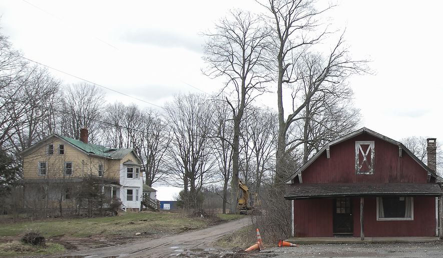 This Friday, April 7, 2017 photo shows the former Ives homestead, left, and barn on the former Chapman property next to Bartlem Park in Cheshire, Conn. The cleanup of a property purchased by Cheshire could include the demotion of the 19th century home that preservationists describe as one of the town’s last examples of a Victorian farmhouse. (Dave Zajac/Record-Journal via AP)