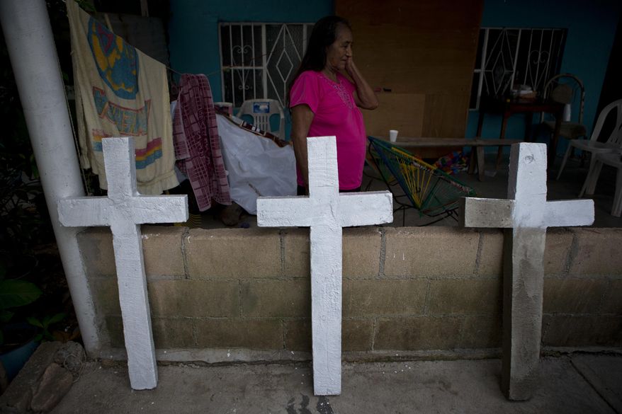 FILE - In this July 1, 2017 file photo, Isabel Osorio Luna, the great-grandmother of the murdered Martinez children, walks past homemade concrete crosses being painted to adorn the simple tombs of the family of six, in Coatzacoalcos, Veracruz State, Mexico. In the Gulf Coast oil city of Coatzacoalcos, in southern Veracruz, state Gov. Miguel Angel Yunes said the slaying of a top gunman in late June prompted the Zetas to kill the entire Martinez family: Clemente; his wife Martimana; 10-year-old Jocelin; Victor Daniel, 8; Angel, 6; and Nahomi, 5.(AP Photo/Rebecca Blackwell, File)