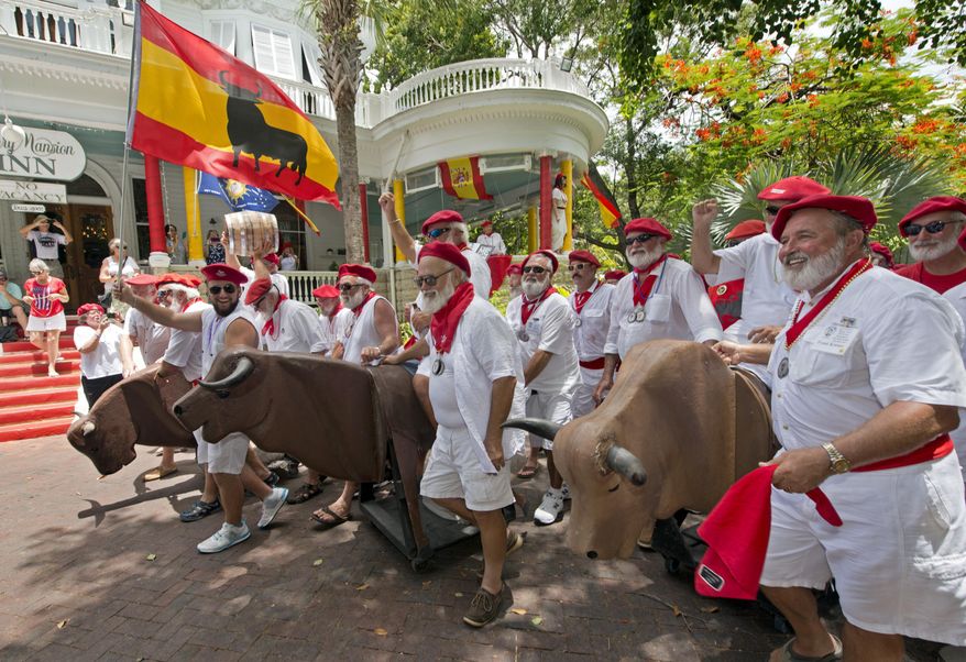 In this photo provided by the Florida Keys News Bureau, Ernest Hemingway look-alikes push fake bulls on wheels through an inn's driveway Saturday, July 22, 2017, in Key West, Fla. Dubbed the Running of the Bulls, the event is an offbeat answer to its namesake in Pamplona, Spain. The activity was part of Key West's Hemingway Days festival that continues through Sunday, July 23. Hemingway lived in Key West in the 1930s. (Andy Newman/Florida Keys News Bureau via AP)