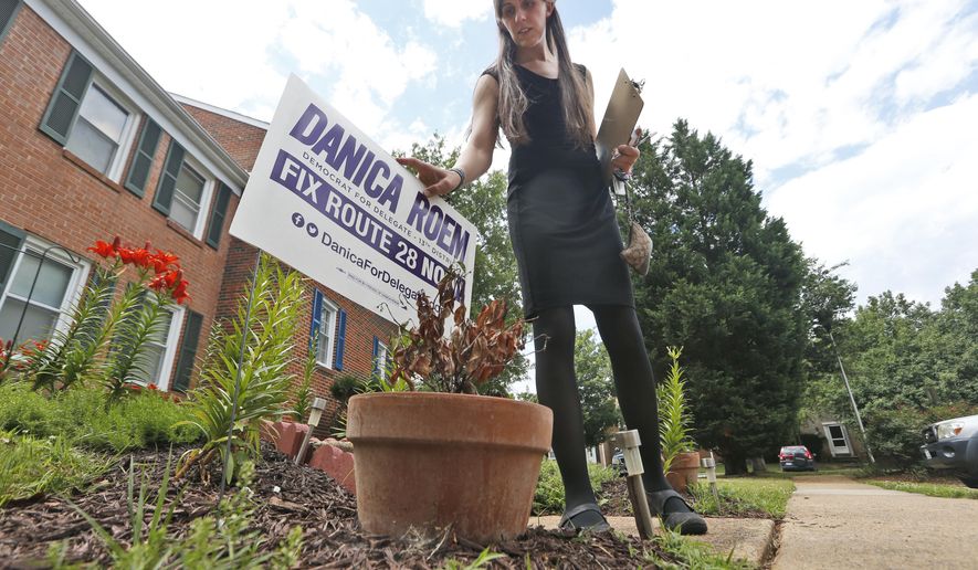 Democratic nominee for the House of Delegates 13th district seat, Danica Roem, places a campaign sign as she canvasses a neighborhood Wednesday, June 21, 2017, in Manassas, Va. Roem is running against Del. Bob Marshall in the 13th House of Delegates District. (AP Photo/Steve Helber)