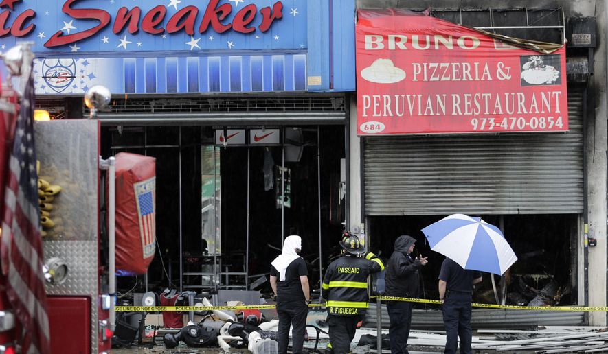 Firefighters and others stand near the scene of a fire in Passaic, N.J., Monday, July 24, 2017. Bruno’s Pizzeria is destroyed and several other businesses are damaged after a massive inferno broke out Sunday night, officials say. (AP Photo/Seth Wenig)