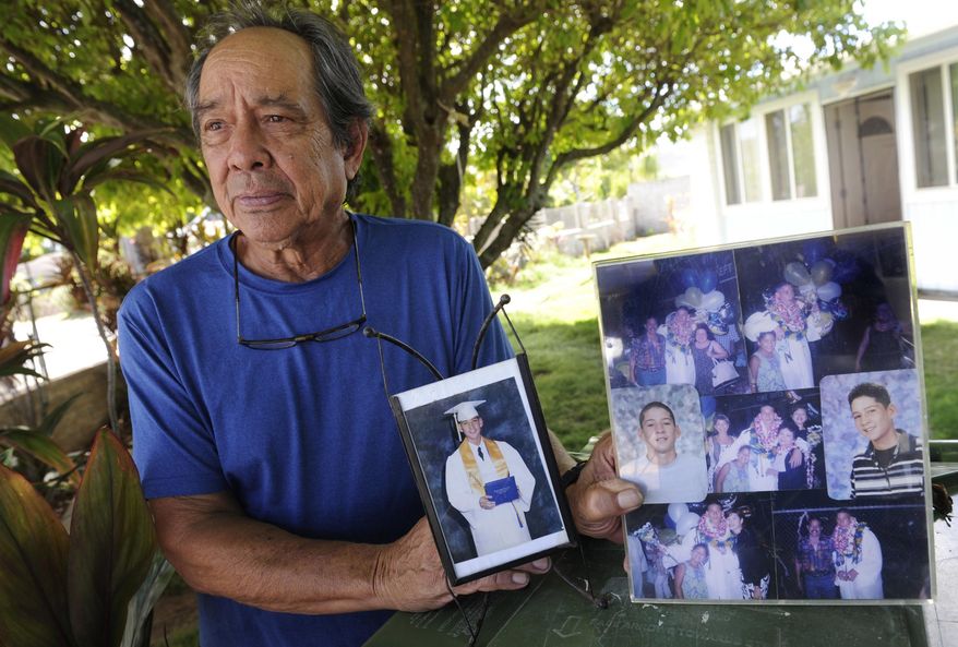 In this July 10, 2017 photo, Clifford Kang, father of soldier Ikaika E. Kang, poses with photos of his son in Kailua, Hawaii. Ikaika E. Kang, an active-duty U.S. soldier, was arrested over the weekend on terrorism charges that accuse him of pledging allegiance to the Islamic State group and saying he wanted to "kill a bunch of people." Ikaika E. Kang is scheduled to appear in federal court for an arraignment Monday, July 24, 2017. (Bruce Asato/The Star-Advertiser via AP)