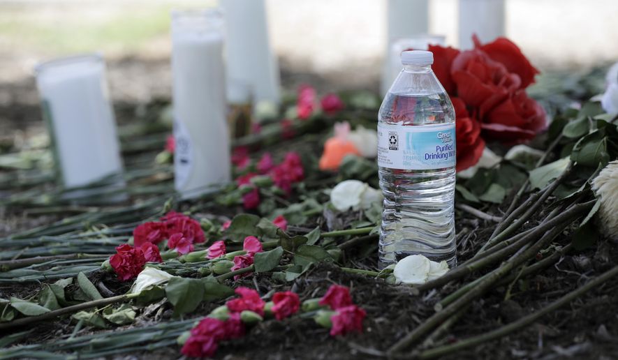 A bottle of water, flowers, candles, and stuffed animals help form a makeshift memorial in the parking lot of a Walmart store near the site where authorities Sunday discovered a tractor-trailer packed with immigrants outside a Walmart in San Antonio, Monday, July 24, 2017. Several people died and others hospitalized after being crammed into a sweltering tractor-trailer in the midsummer Texas heat, according to authorities in what they described as an immigrant-smuggling attempt gone wrong. (AP Photo/Eric Gay)