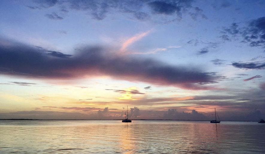 This photo taken Wednesday, June 14, 2017, shows a colorful sunset viewed from the Caribbean Club at Key Largo, Florida. The roadside landmark is on the Overseas Highway, which links Florida's mainland with Key West. Some tourists drive straight through the chain of islands without exploring sights and attractions that lie along the road. (AP Photo/Jay Reeves)