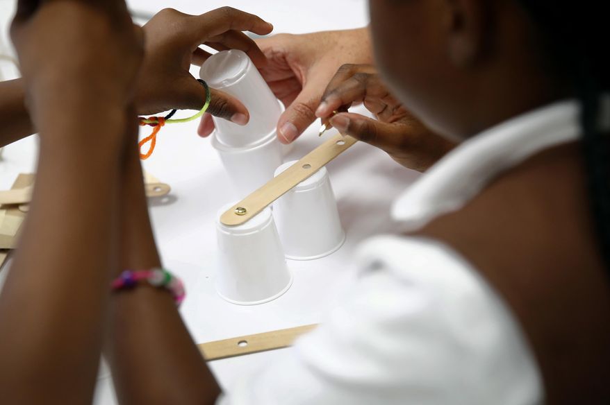 In this July 21, 2017 photo, members of the Girl Scouts of Central Maryland use various materials to build simple robotic arms as they participate in an activity introducing them to the world of robotics in Owings Mills, Md. The Girl Scouts of the USA is unveiling a major push this week into furthering the interest of girls in science, engineering, technology and math through 23 new badges, some of which were requested by scouts themselves in a survey. (AP Photo/Patrick Semansky)