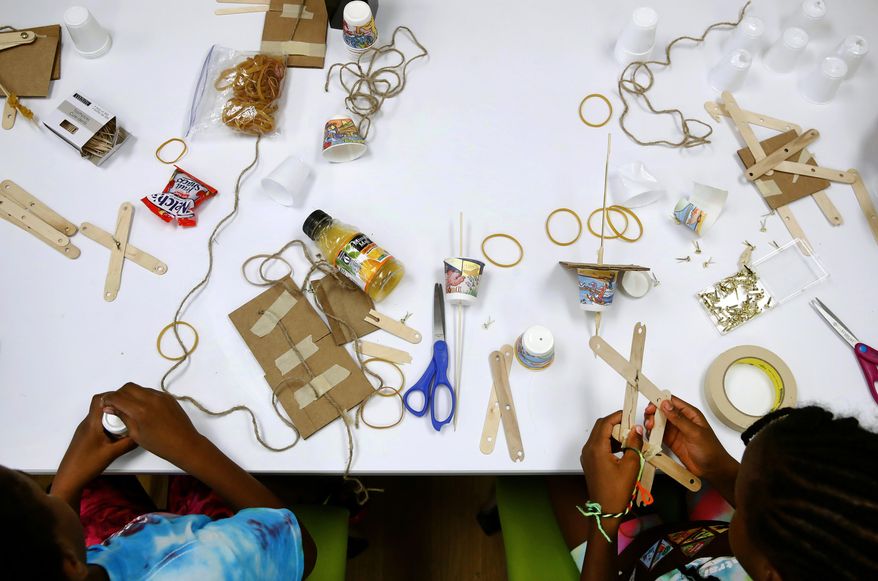 In this July 21, 2017 photo, members of the Girl Scouts of Central Maryland use various materials to build simple robotic arms as they participate in an activity introducing them to the world of robotics in Owings Mills, Md. The Girl Scouts of the USA is unveiling a major push this week into furthering the interest of girls in science, engineering, technology and math through 23 new badges, its largest addition of new badges in a decade. (AP Photo/Patrick Semansky)