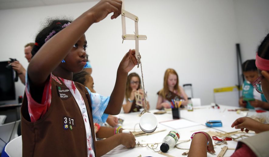 ** PLEASE HOLD FOR MOVEMENT ** In this July 21, 2017 photo, Cayla Hicks, age 7, a member of the Girl Scouts of Central Maryland, creates a simple robotic arm out of wooden sticks, fasteners and rope during an activity introducing the world of robotics in Owings Mills, Md. Girl Scouts of all ages can now earn 23 new badges focused on science, technology, engineering and math, the largest addition of new badges in a decade. The effort takes a progressive approach to STEM and also nudges girls to become citizen scientists using the great outdoors as their laboratory. (AP Photo/Patrick Semansky)