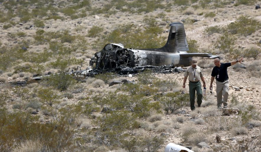 Officials walk from the crash site after a vintage single-engine British-built military jet crashed and burned in the desert just after takeoff from the Henderson Executive Airport in Henderson, Nev. Monday, July 24, 2017. The pilot escaped serious injury, authorities said. (Steve Marcus/Las Vegas Sun via AP)