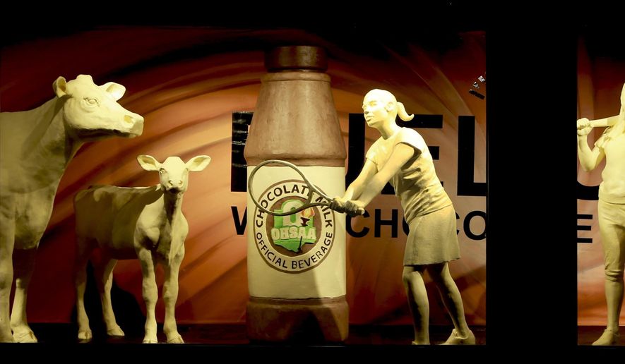 This undated photo, shows the traditional butter cow and calf that are now accompanied by four young student-athletes and a larger-than-life bottle of the official beverage that fuels them, chocolate milk. (American Dairy Association Mideast via AP)