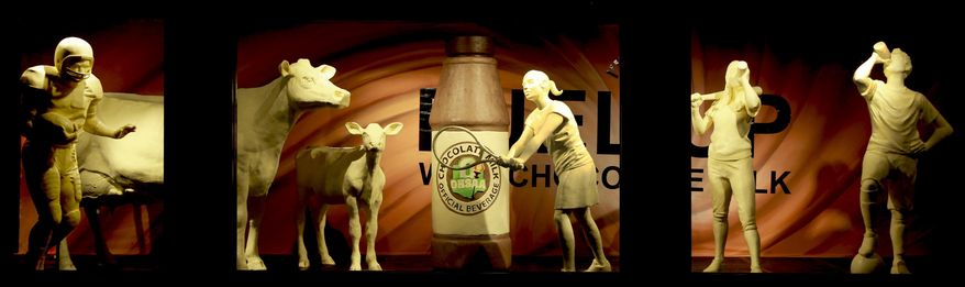 This undated photo, shows the traditional butter cow and calf that are now accompanied by four young student-athletes and a larger-than-life bottle of the official beverage that fuels them, chocolate milk. (American Dairy Association Mideast via AP)
