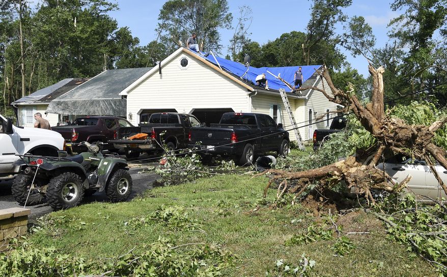 Residents work to secure a tarp on the roof of their home in Bay City, Md., Monday, July 24, 2017. A National Weather Service team is headed to Maryland's Eastern Shore to determine whether a tornado touched down there. (Paul W. Gillespie/The Baltimore Sun via AP)