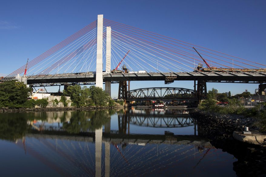 The main span of the old Kosciuszko Bridge sits on two barges beneath the new bridge, Wednesday, July 26, 2017, in New York. The old bridge, which opened in 1939, is being demolished after the new bridge opened in April. (AP Photo/Mark Lennihan)