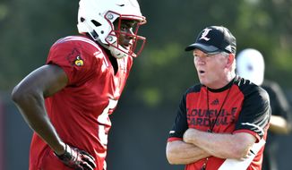 FILE - In this Aug. 5, 2016, file photo, Louisville head football coach Bobby Petrino, right, talks with freshman wide receiver Seth Dawkins as they go through workouts at their first public practice, in Louisville Ky. The Cardinals begin fall practice Monday with holes to fill on both sides of the ball after losing their final three games. (AP Photo/Timothy D. Easley, File)