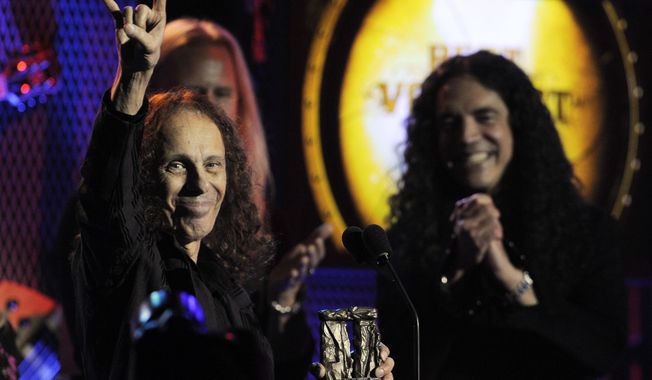 FILE - In this April 8, 2010, file photo, Ronnie James Dio, left, celebrates after receiving the Best Vocalist award at the second annual Revolver Golden Gods Awards in Los Angeles. Rolling Stone reported July 26, 2017, that Dio, who died in 2010, would tour again in hologram form. (AP Photo/Chris Pizzello, File)