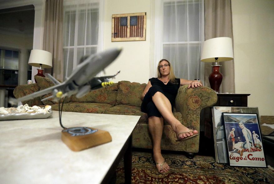 A model F18 jet sits on a coffee table as Alaina Kupec poses for a photograph at her home, Wednesday, July 26, 2017, in Orange, N.J. Kupec, a transgender woman who worked with pilots who flew F18 jets while serving as a Navy intelligence officer from 1992 until 1995, said she felt "heartbreak" after she heard about Trump's Twitter pronouncement banning transgender people from military service. The 48-year-old publicly transitioned to life as a woman in 2013. (AP Photo/Julio Cortez)