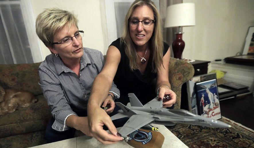 Alaina Kupec, right, and her wife Kathy Brennan work on putting bombs on a model F18 jet after pulling it out from a moving box in the home they just moved in to, Wednesday, July 26, 2017, in Orange, N.J. Kupec, a transgender woman who worked with pilots who flew F18 jets while serving as a Navy intelligence officer from 1992 until 1995, said she felt "heartbreak" after she heard about Trump's Twitter pronouncement banning transgender people from military service. The 48-year-old publicly transitioned to life as a woman in 2013. (AP Photo/Julio Cortez)