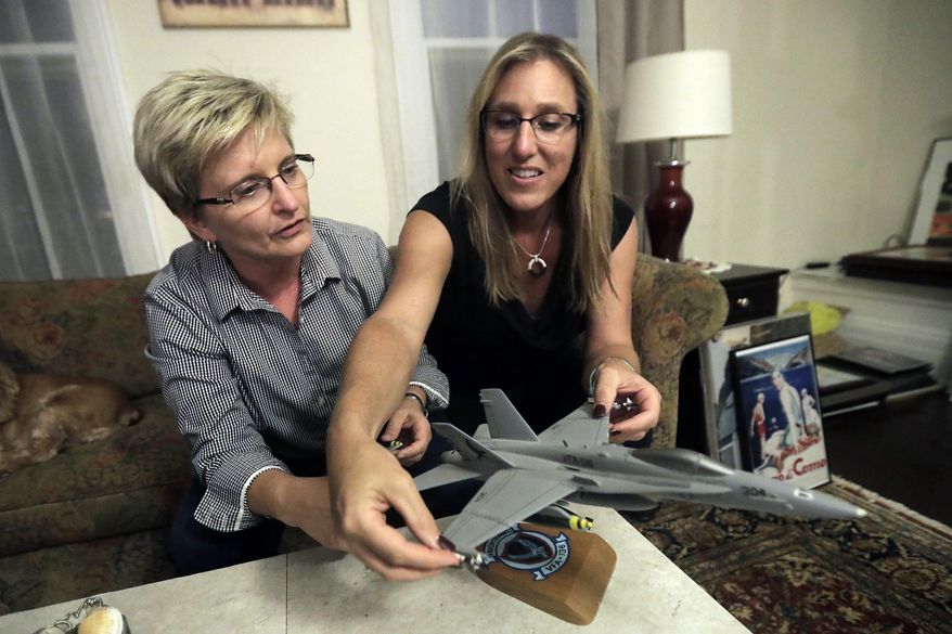 Alaina Kupec, right, and her wife Kathy Brennan work on putting bombs on a model F18 jet after pulling it out from a moving box in the home they just moved in to, Wednesday, July 26, 2017, in Orange, N.J. Kupec, a transgender woman who worked with pilots who flew F18 jets while serving as a Navy intelligence officer from 1992 until 1995, said she felt "heartbreak" after she heard about Trump's Twitter pronouncement banning transgender people from military service. The 48-year-old publicly transitioned to life as a woman in 2013. (AP Photo/Julio Cortez)
