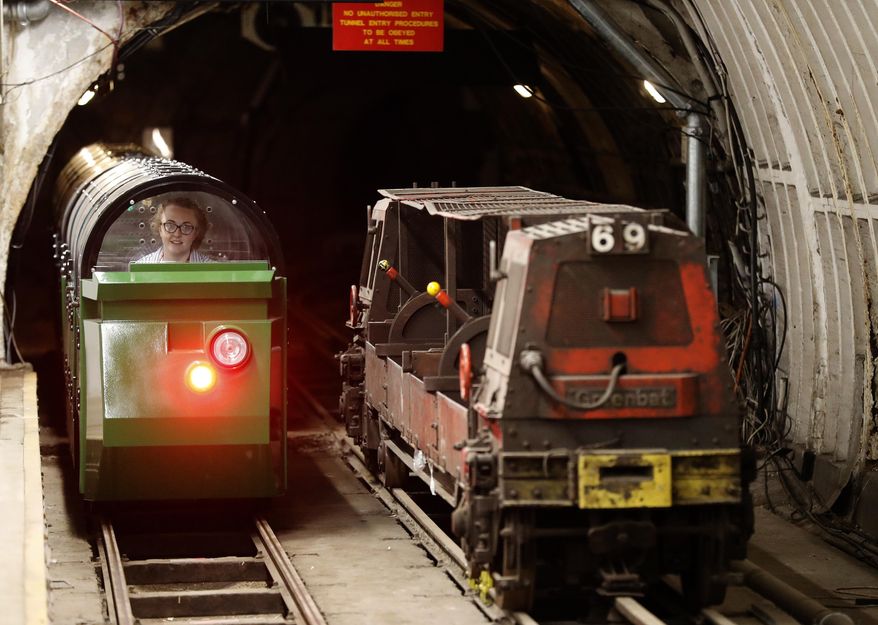 A passenger train rides through the Mail Rail tunnels that is included in the Postal Museum in London, Wednesday, July 26, 2017. London's newest tourist attraction is perfect for underground explorers. It's not ideal for the claustrophobic. A visit to Mail Rail, a subterranean train network that once carried millions of letters a day across the city, involves a cramped journey through dark tunnels 70 feet (21 meters) below the surface, on a very small train. It's atmospheric, but not roomy. (AP Photo/Frank Augstein)
