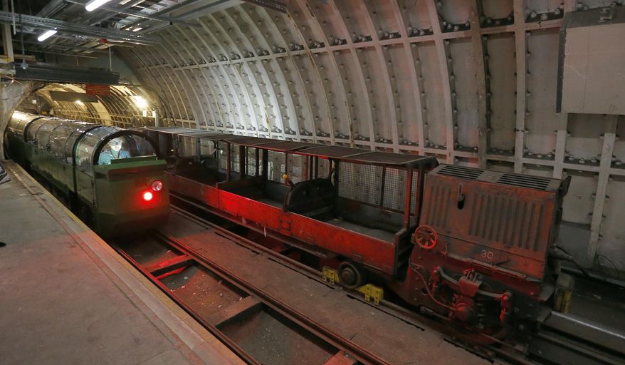 A passenger train rides through the Mail Rail tunnels that is included in the Postal Museum in London, Wednesday, July 26, 2017. London's newest tourist attraction is perfect for underground explorers. It's not ideal for the claustrophobic. A visit to Mail Rail, a subterranean train network that once carried millions of letters a day across the city, involves a cramped journey through dark tunnels 70 feet (21 meters) below the surface, on a very small train. It's atmospheric, but not roomy. (AP Photo/Frank Augstein)