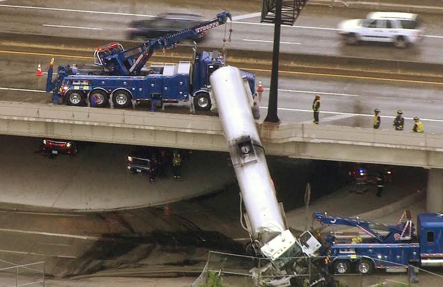 In this photo from video provided by KMOV-TV, emergency responders work to lower a tanker truck to the ground after it crashed off an Interstate 44 overpass in downtown St. Louis, Thursday, July 27, 2017. (KMOV-TV via AP)