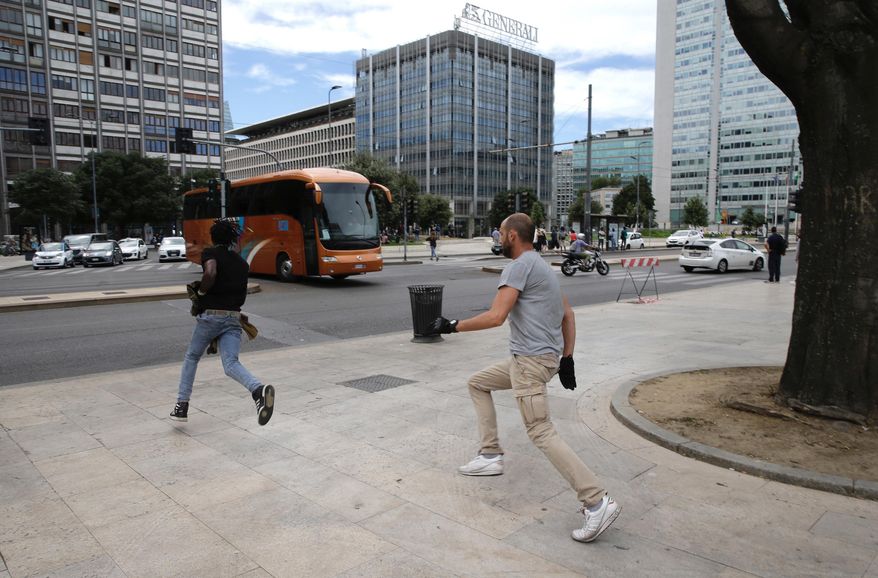 A plain clothes policeman, right, chases a man during a blitz outside Milan’s main train station, Italy, Wednesday, July 26, 2017. Authorities have detained several dozen people in response to an increasing public security issue as the city deals with a new wave of migrants. (AP Photo/Luca Bruno)